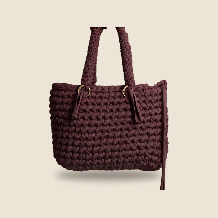 Sac à main en crochet prune, anses tressées et anneaux dorés, sur fond uni