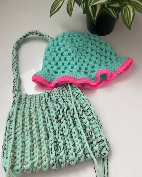 Turquoise crochet bucket hat with a wavy neon pink brim, resting on a mint green crochet bag